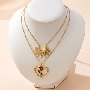 Collana a doppio strato dorata con ciondoli a sole e cuore rosa su supporto