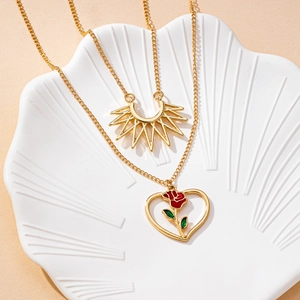 Collana doppia dorata con pendente a sole e cuore con rosa su vassoio a conchiglia