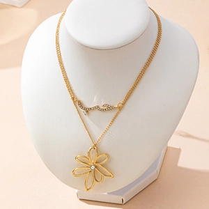 Collier double rang doré avec pendentif fleur et breloque arabe sur un présentoir buste