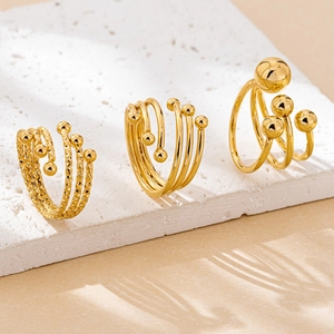 Detailed view of three gold layered rings with bead accents on a textured stone stand
