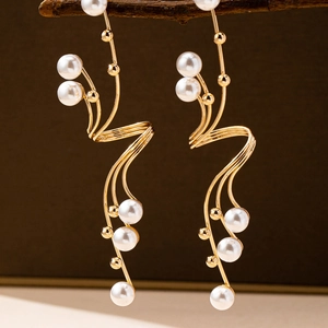 Detail of elegant gold branching earrings with white pearls hanging on a natural branch