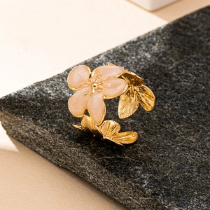 Détail d'une bague fleur de cerisier en émail rose avec pétales dorés sur pierre