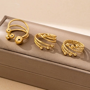 Three-piece set of golden minimalist open rings with beads on a brown jewelry box