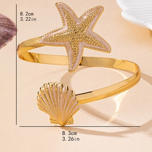 Adjustable gold ocean theme arm cuff with enamel starfish and seashell charms on sand