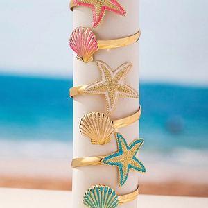 Adjustable gold ocean arm cuff with colorful enamel starfish and seashell charms