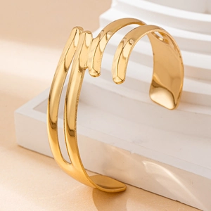 Detailed view of adjustable golden cutout geometric bangle on white minimalist props
