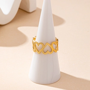Minimalist gold heart-shaped hollow ring with matte texture on a white display stand