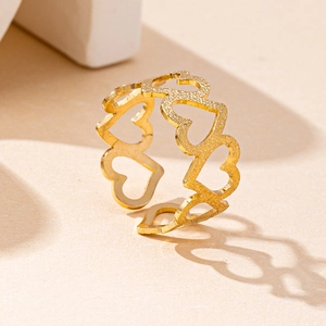 Detail of gold hollow heart ring with matte texture casting heart-shaped shadow