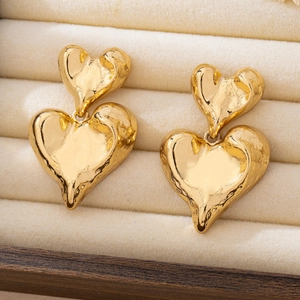 Detailed macro view of gold double heart earrings with unique hammered lava texture