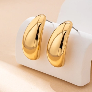 Minimalist gold teardrop stud earrings with a polished mirror finish on a white stand
