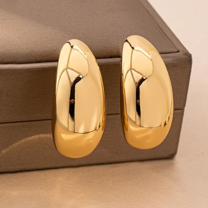 Macro shot of minimalist gold teardrop earrings with a polished mirror finish on jewelry box