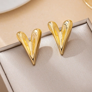 Close-up of shiny gold heart stud earrings on a premium champagne satin jewelry box