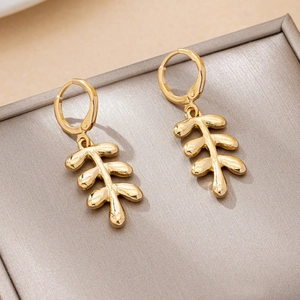 Minimalist gold leaf branch drop earrings with polished metallic finish on a display box