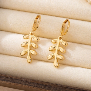 Detail of gold leaf earrings with polished finish on a beige velvet jewelry display