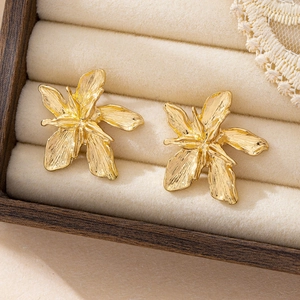 Exquisite gold floral earrings with layered textured petals in a wooden jewelry box