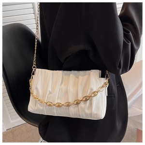 Close-up of white pleated cloud bag with elegant gold chain and thin leather shoulder strap