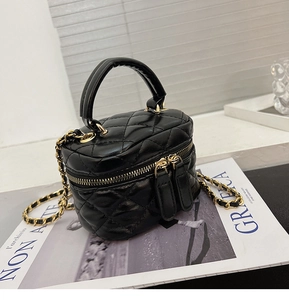 Detail of black quilted leather vanity case with gold chain strap and top handle