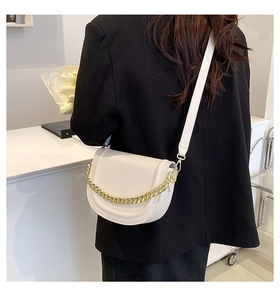 Chic beige saddle bag with gold chain strap shown on black blazer for stylish contrast