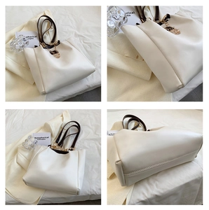 Detail view of large cream tote bag with dark brown handles and golden chain accents