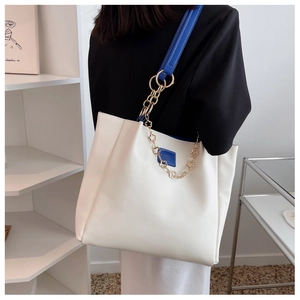 Detailed shot of large white tote bag with blue trim and elegant gold floral chain