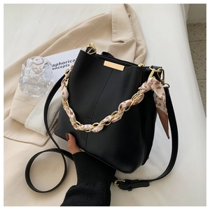 Detail of a black leather bucket bag featuring a leopard silk scarf wrapped gold chain handle