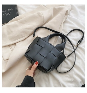 Close-up of a mini black woven leather bucket bag with top handles and slender strap