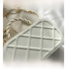 Detailed macro view of white quilted leather bag with elegant metallic chain and twist handle
