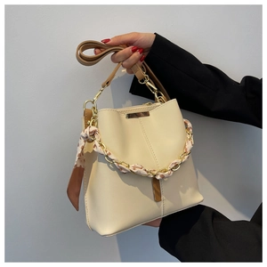 Detail of cream bucket bag with gold chain handle and floral scarf wrap detail