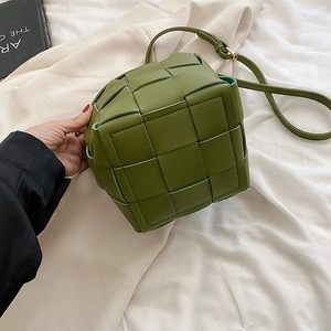 Detail of green woven bucket bag showing Intrecciato leather texture and adjustable strap
