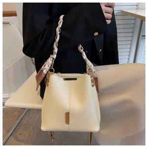Detail of cream white bucket bag with gold chain and floral scarf woven handle