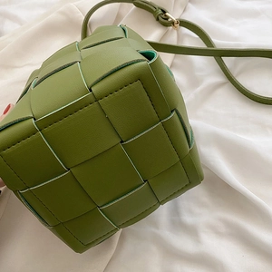 Detail of avocado green woven leather texture with cross-stitch pattern and gold metal buckle