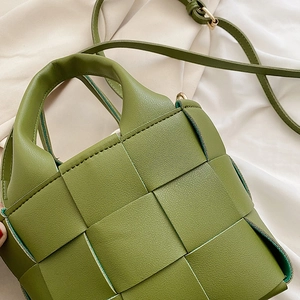 Detail of olive green woven leather handbag featuring gold-tone hardware and textured finish