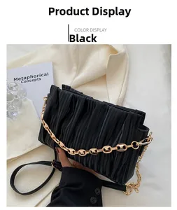 Detail of black pleated crossbody bag with chunky gold chain and leather strap