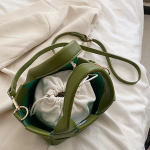 Detailed view of olive green woven bucket bag with white canvas drawstring inner pouch