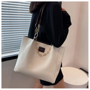 Close-up of cream PU leather tote bag with gold flower chain and shoulder strap detail