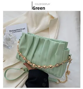Detail of light green pleated crossbody bag with gold chain and elegant setup
