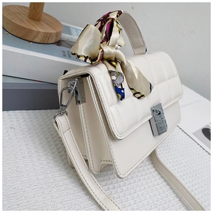 Detail of cream quilted handbag with floral silk scarf handle and silver lock
