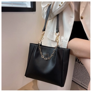 Detail of black leather tote bag featuring gold petal chain and white contrast stitching