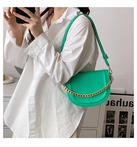 Detail of bright green saddle bag featuring golden chain and premium leather texture