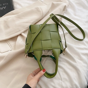Detail view of a green woven bucket bag with leather texture and drawstring liner