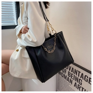 Detail of black large capacity tote bag with gold chain strap and textured finish