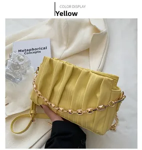 Close-up of yellow pleated crossbody bag with thick gold chain and faux leather strap