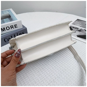 Detail view of white leather crossbody bag with dual-compartment accordion structure design