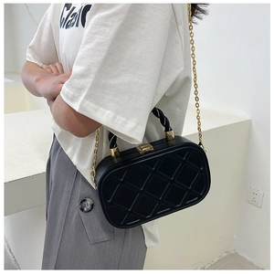 Close-up of black quilted crossbody bag with gold chain strap and twisted top handle