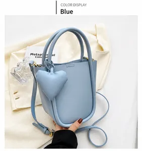 Dettaglio della borsa a secchiello azzurra con ciondolo a cuore e metallo oro