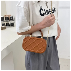 Detail view of brown quilted crossbody bag with spiral handle and gold chain strap