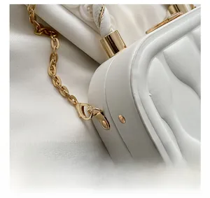 Detailed macro view of gold-tone metal hook and quilted texture on white leather bag