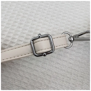 Detail of adjustable cream white leather strap with polished silver metal buckle and hook