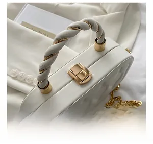 Close-up of white quilted box bag featuring unique metal chain handle and gold clasp