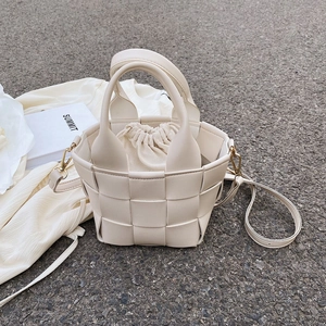 Detail view of woven cream bucket bag with drawstring inner pouch and gold hardware